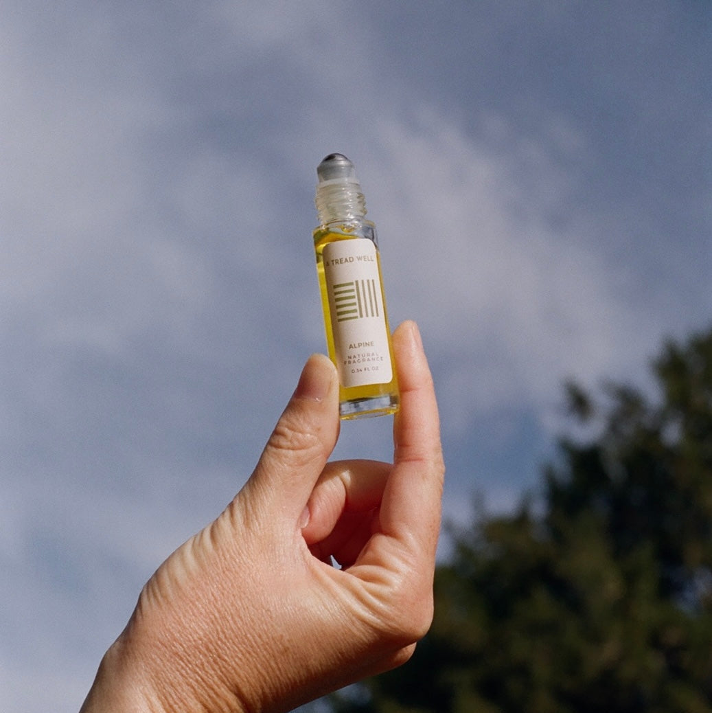 Hand holding a small bottle with a label against a cloudy sky