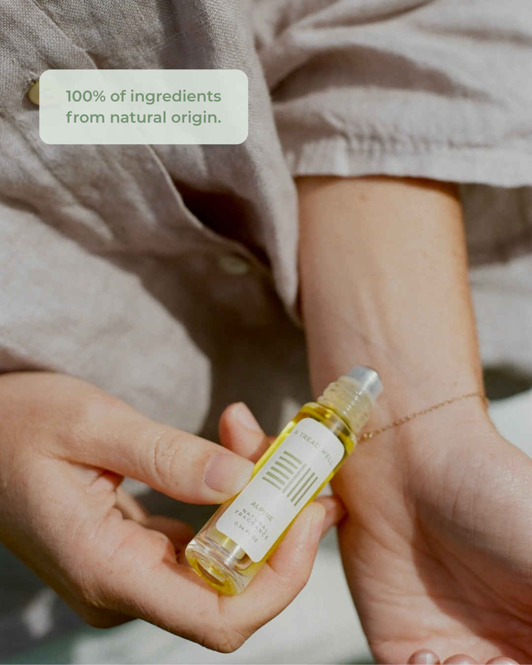 Person holding a small bottle of alpine fragrance with a label indicating natural ingredients.