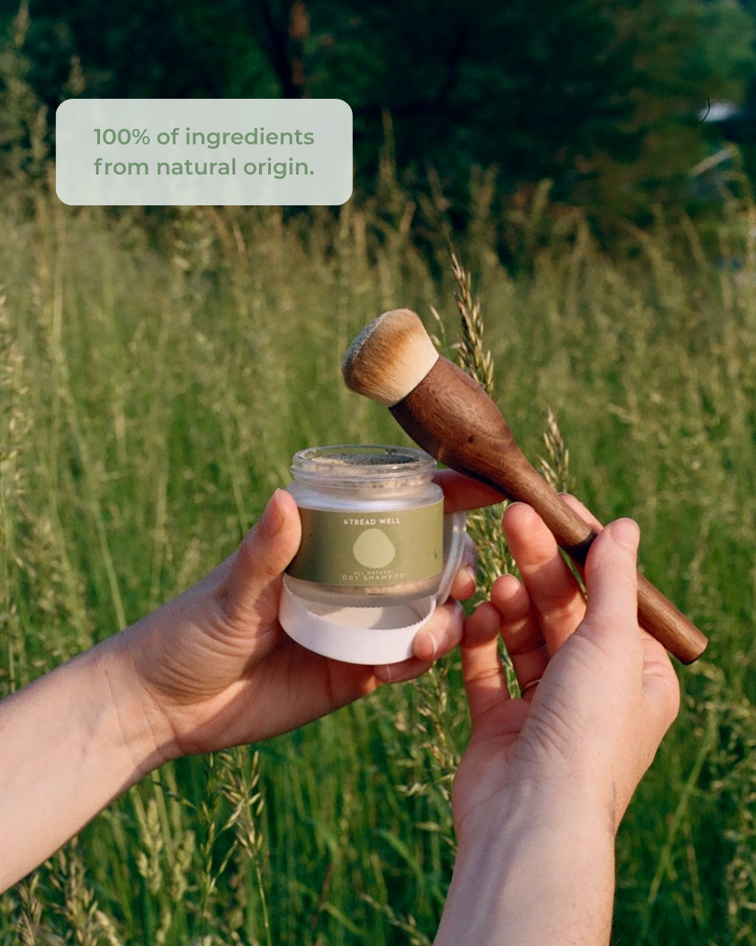 Dry shampooo being held over blurred grass, with text about organic and natural ingredients