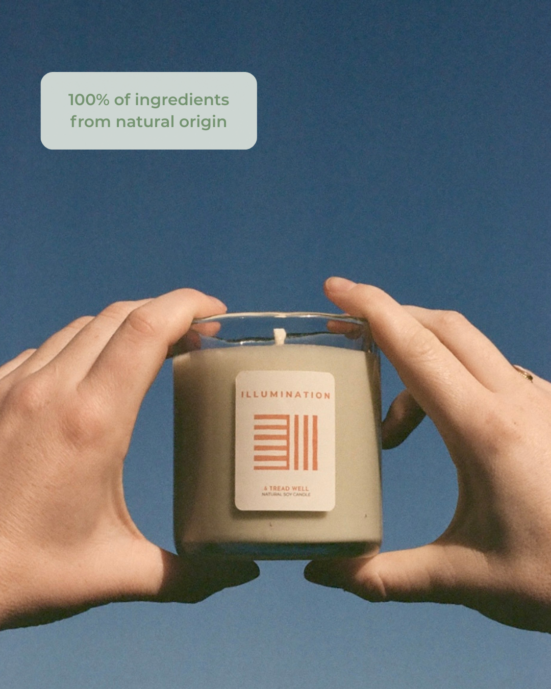Two hands holding a candle labeled 'Illumination' against a blue background with text about natural ingredients.