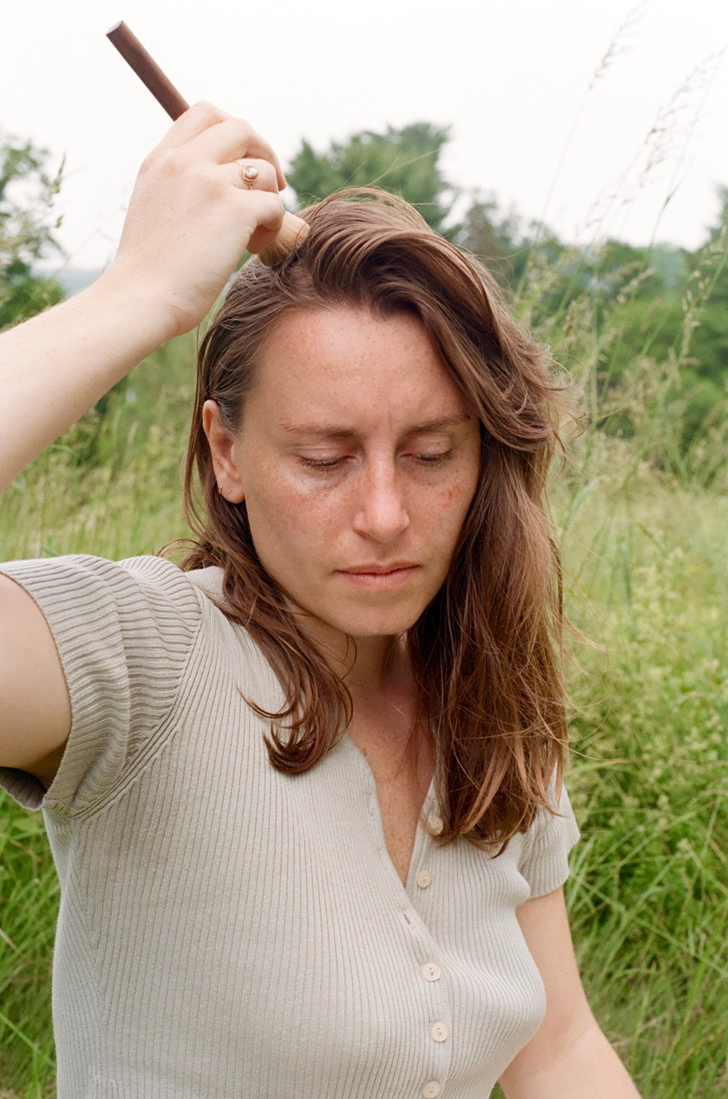 Woman dry shampooing her hair outdoors in a natural setting