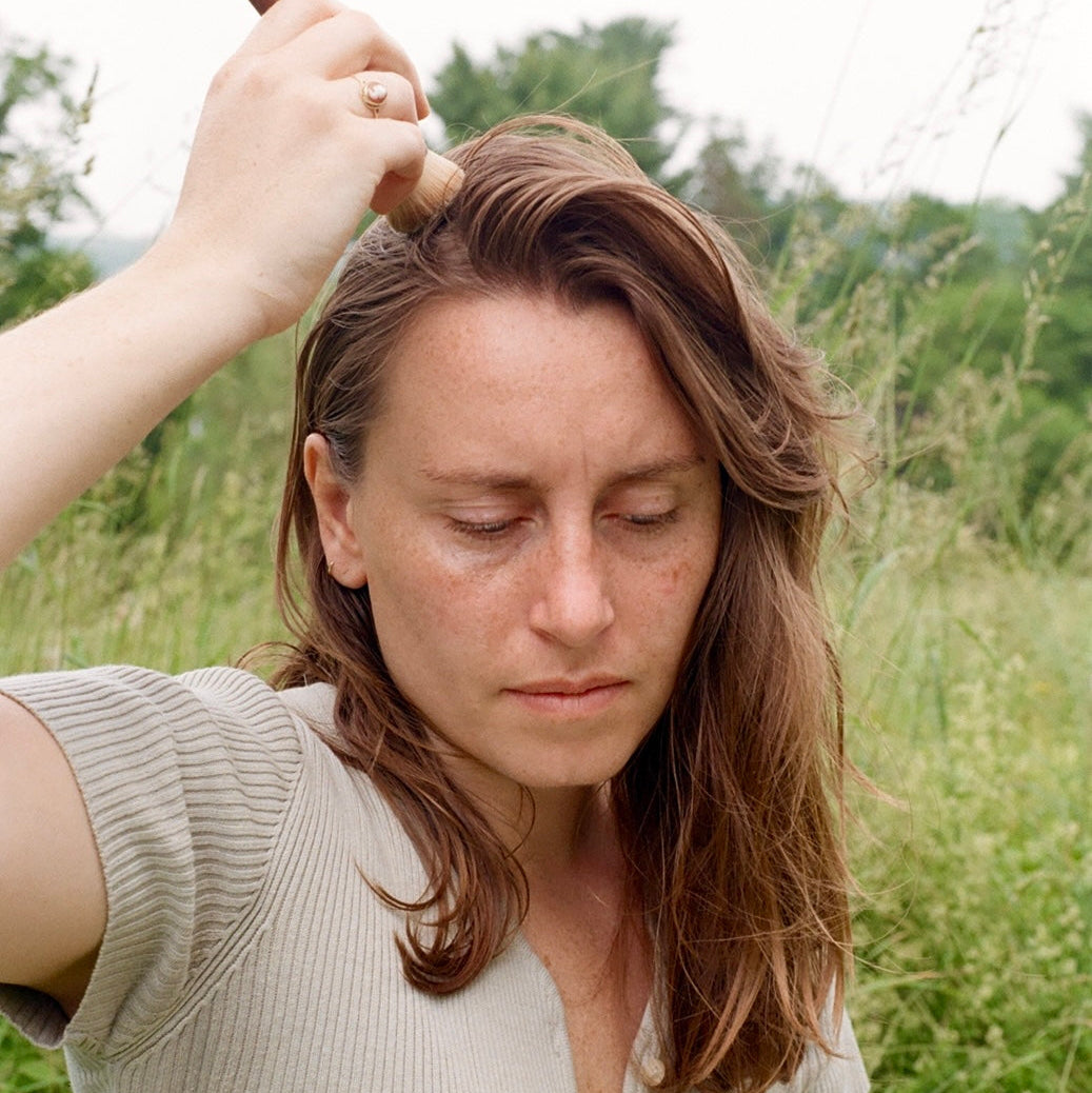 Woman dry shampooing her hair outdoors in a natural setting