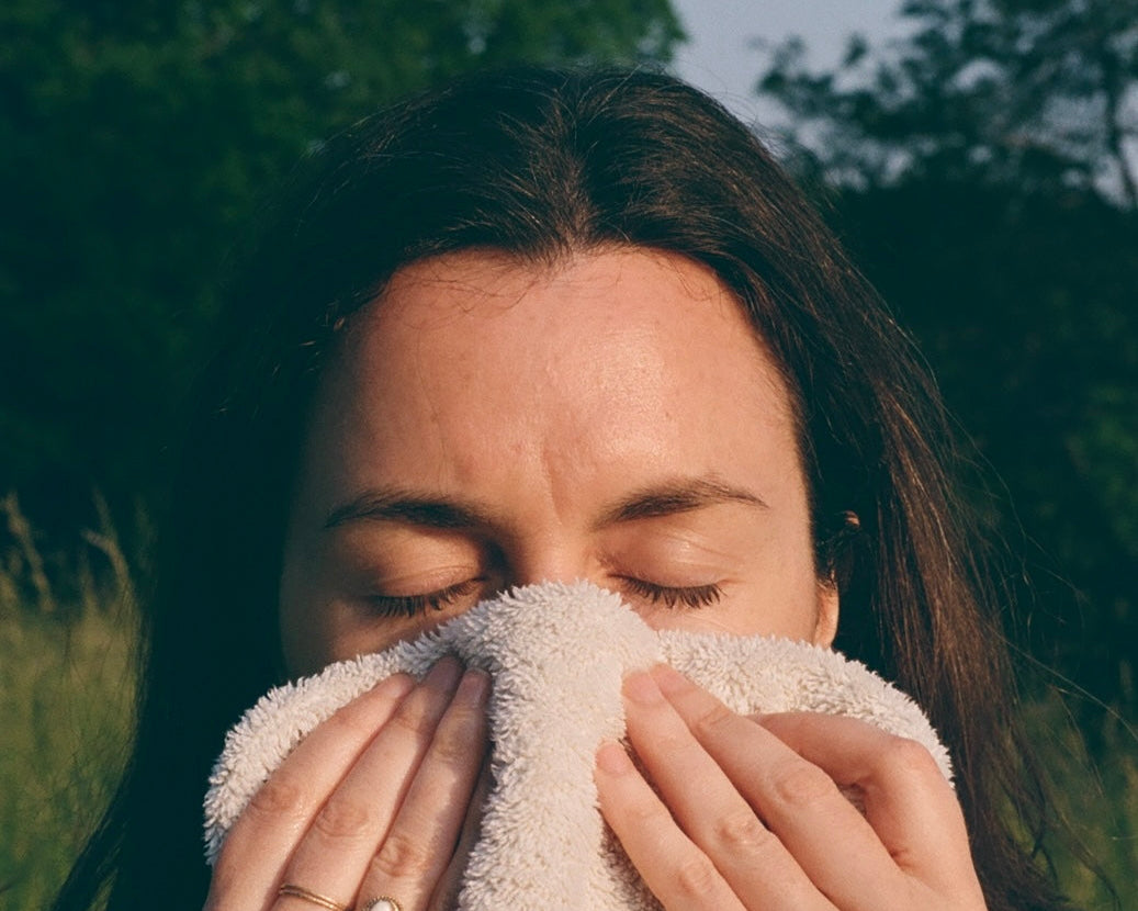 Woman wiping her face with a towel outdoors