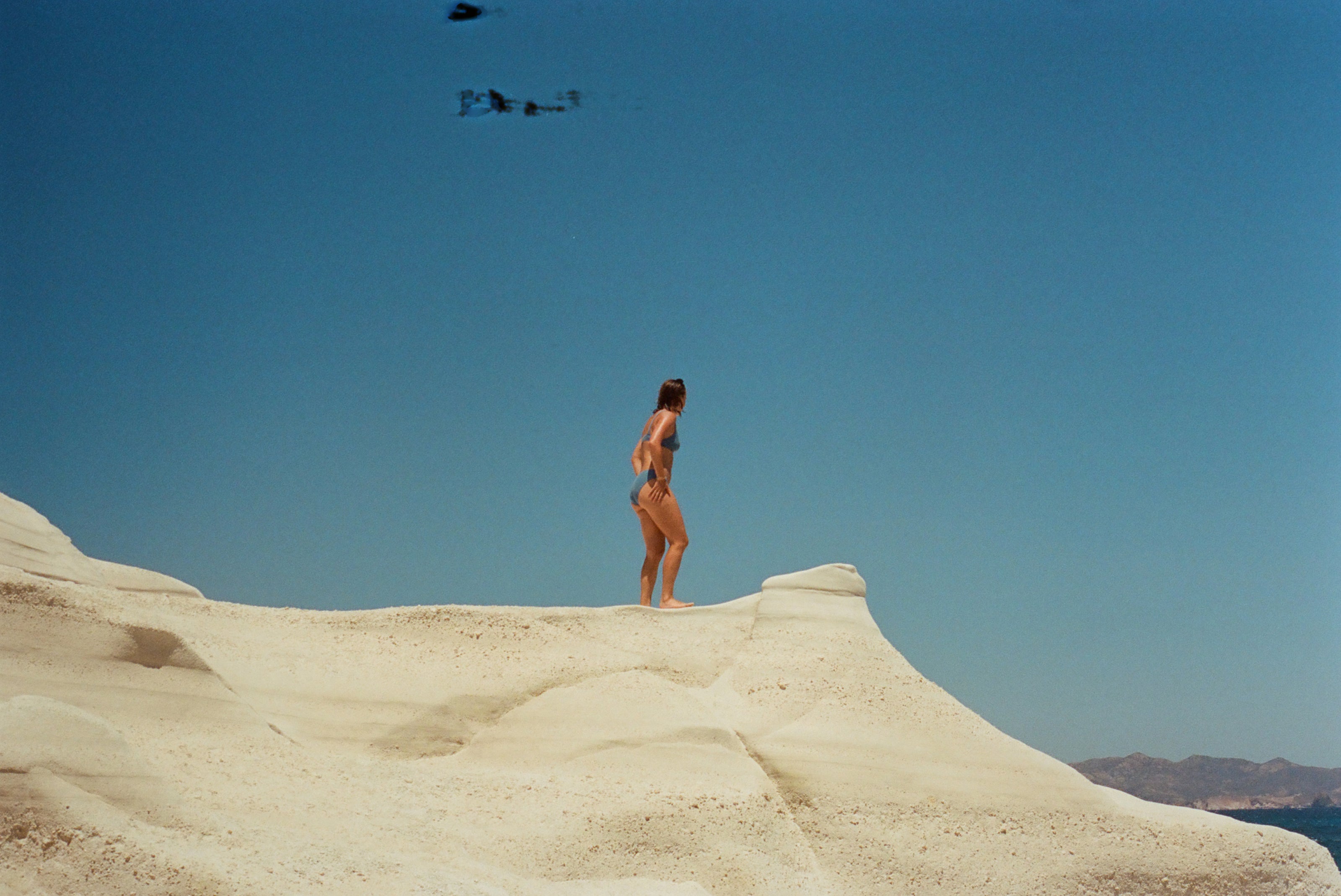 a person in a garment standing on a sand dune