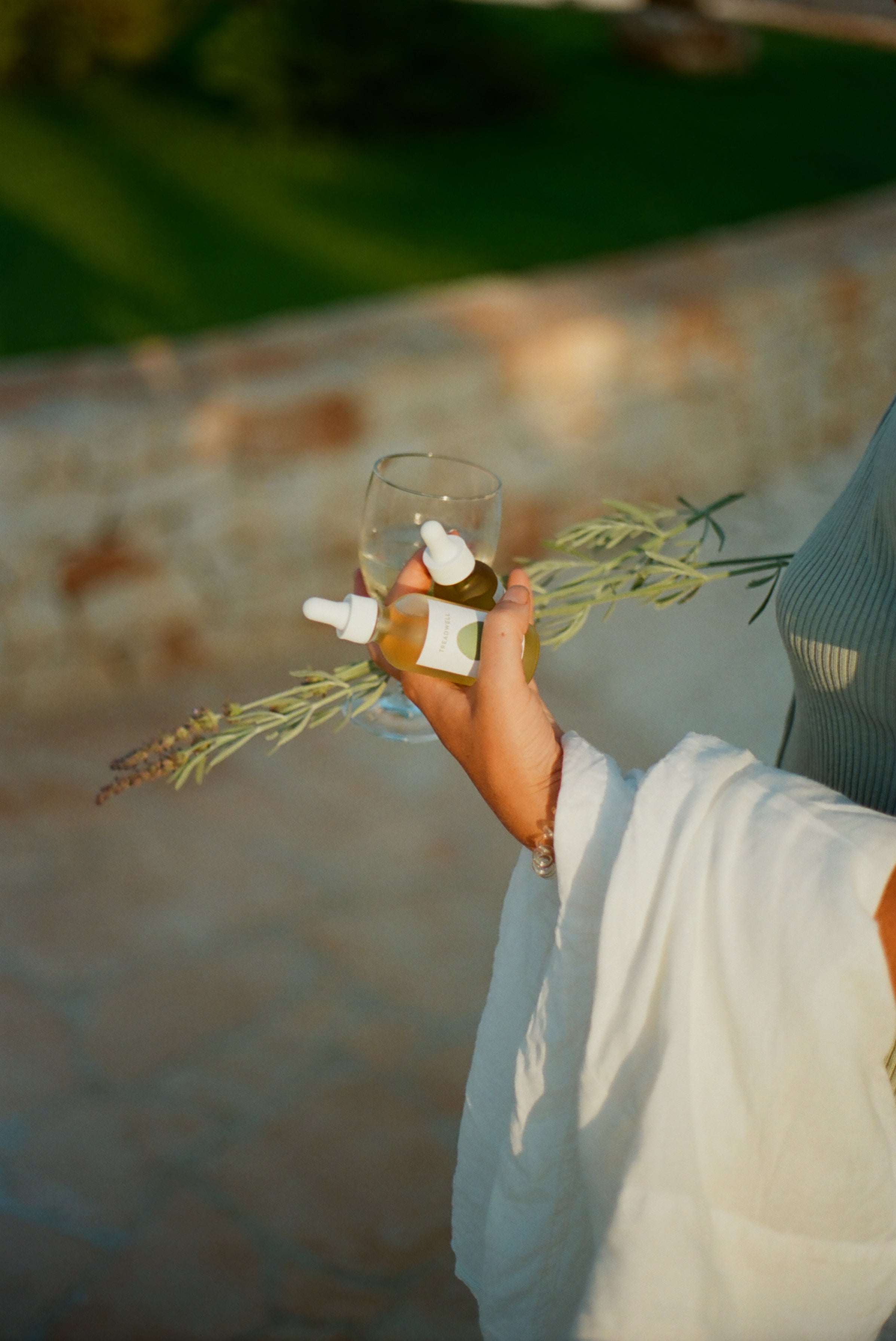 a person holding a glass with two bottles and a plant