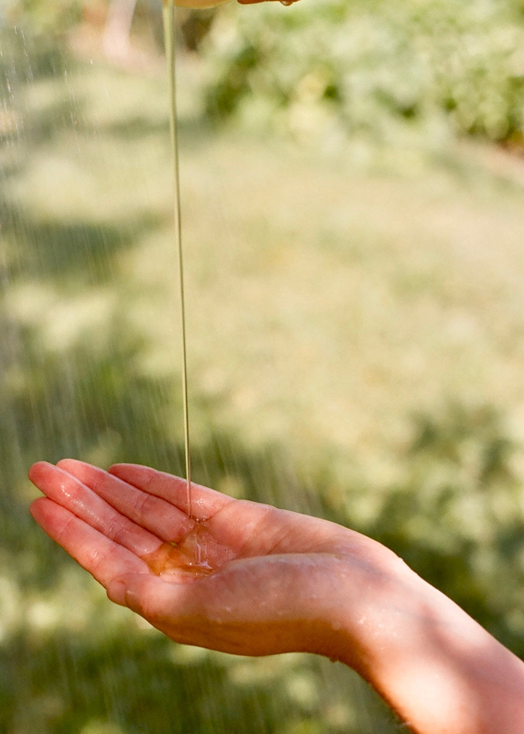 Hand catching dripping soap with a blurred natural background