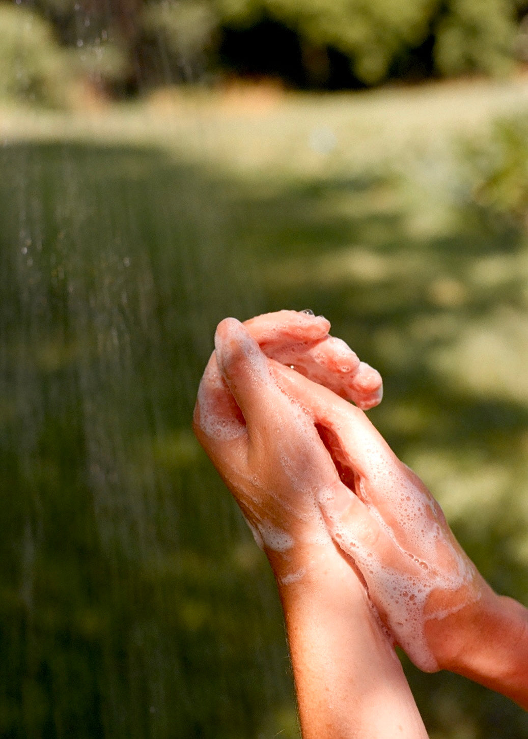 Hands with soap bubbles against a blurred natural background
