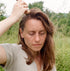 Woman dry shampooing her hair outdoors in a natural setting