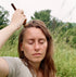 Woman dry shampooing her hair outdoors in a field