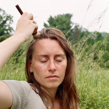 Woman dry shampooing her hair outdoors in a field