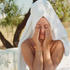 Woman with a towel wrapped around her head, outdoors with trees in the background