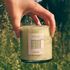 Hand holding a candle labeled 'Alpine' against a natural background