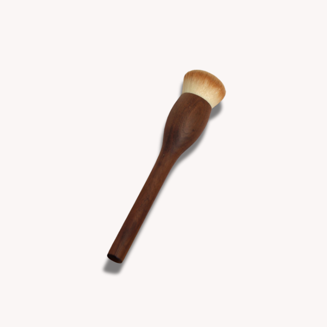 Wooden makeup brush with a white bristle head on a light gray background