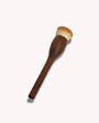 Wooden makeup brush with a white bristle head on a light gray background