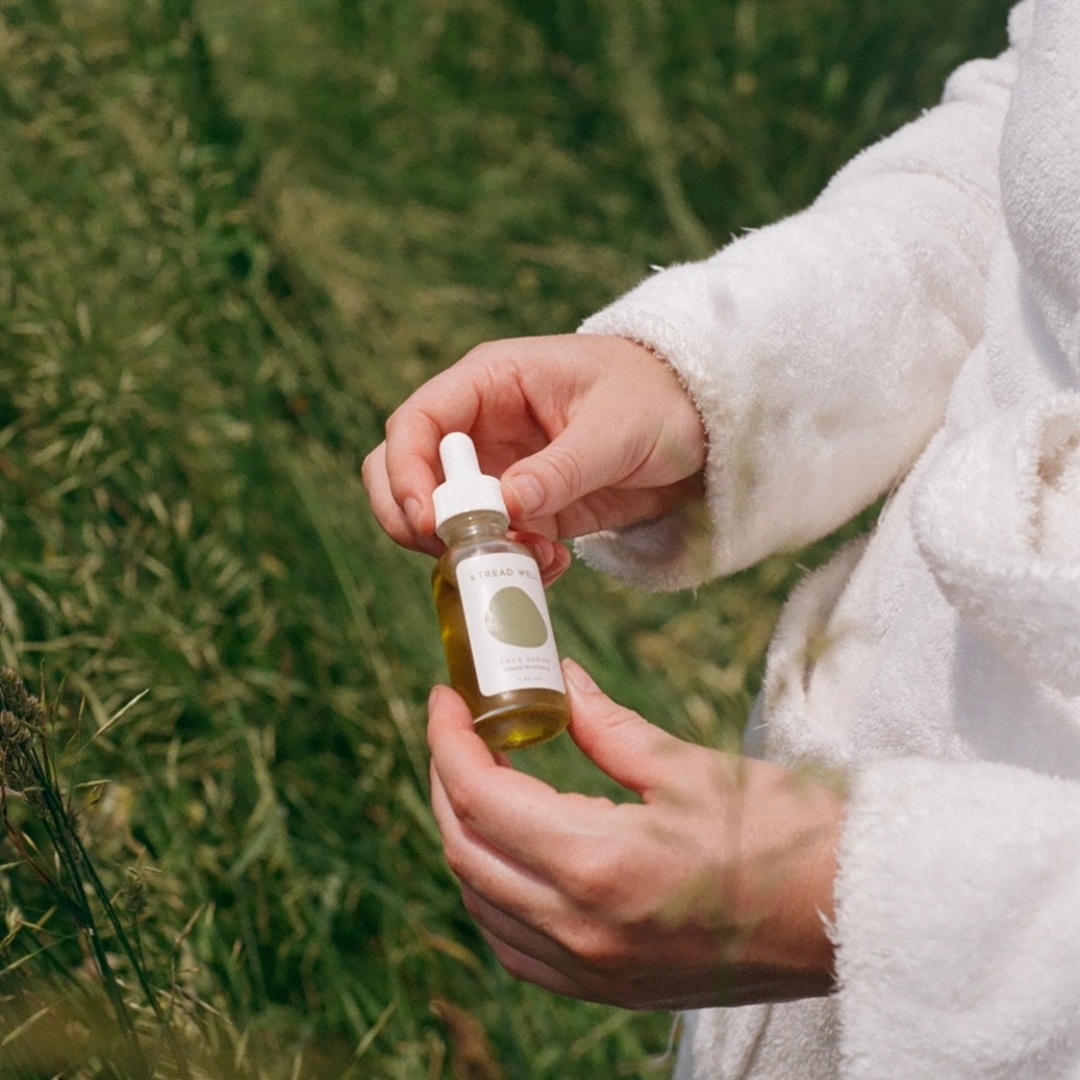 Person holding a dropper bottle with a natural background