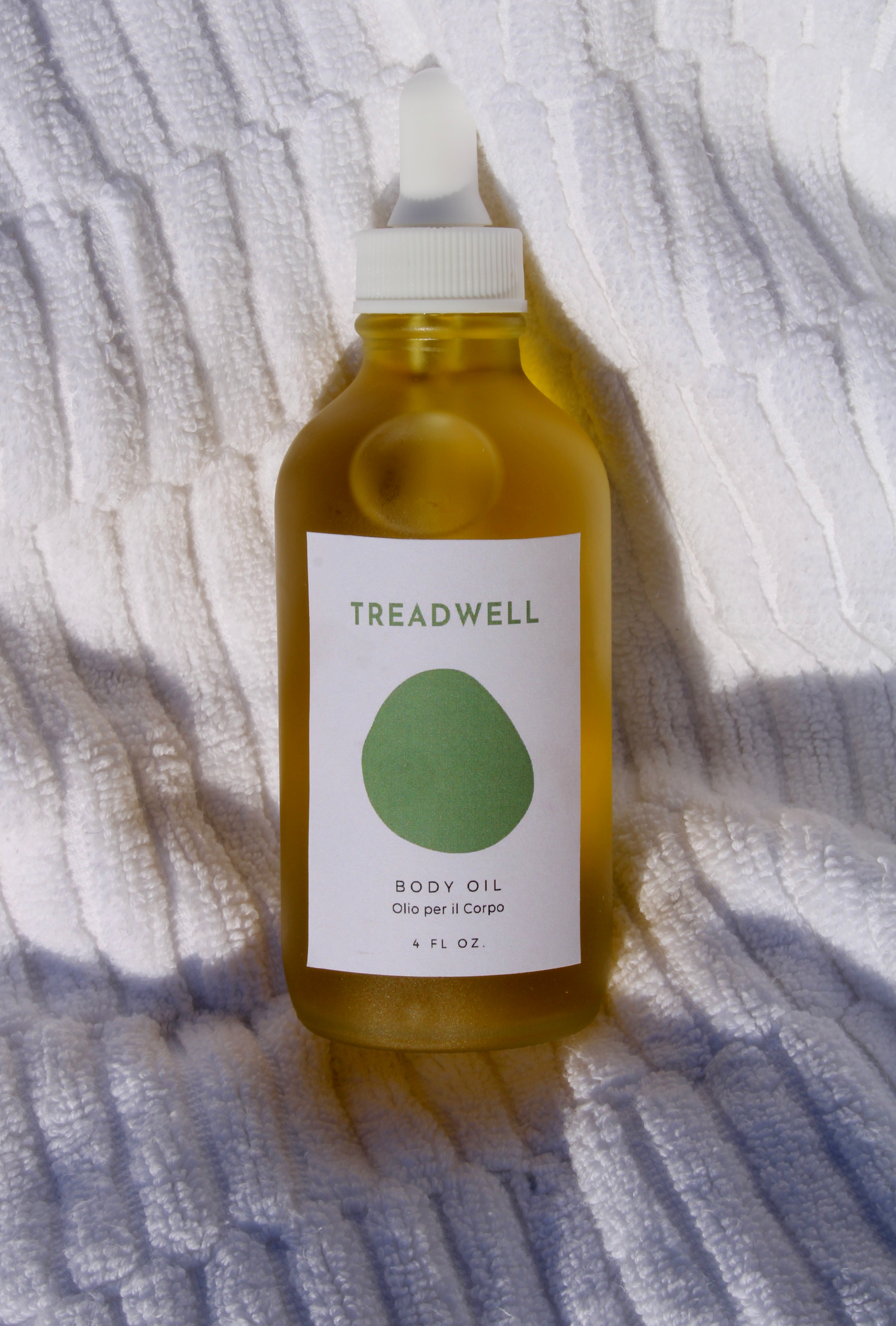 a bottle of body oil on a white towel