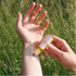 Person applying a fragrance oil to their wrist in a grassy field.