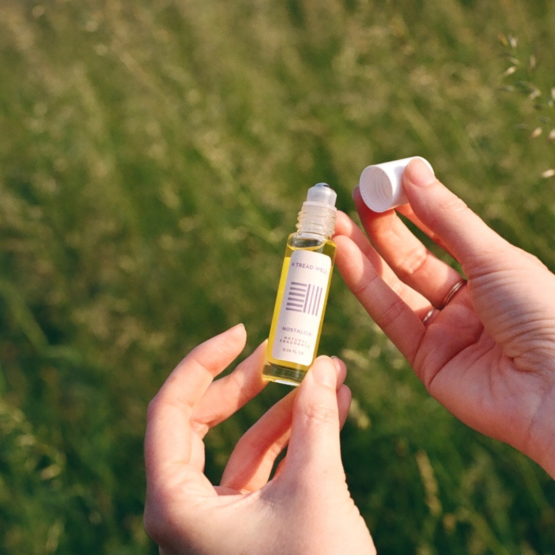 Small bottle with a dropper held by hands against a blurred green field background