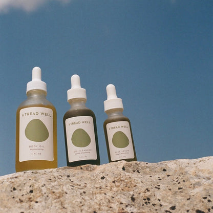 Three bottles of Thread Well products on a rock with a blue sky background
