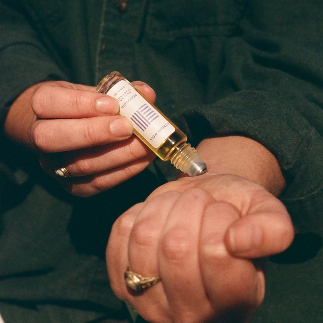 Person holding a small bottle with a dropper against a dark background