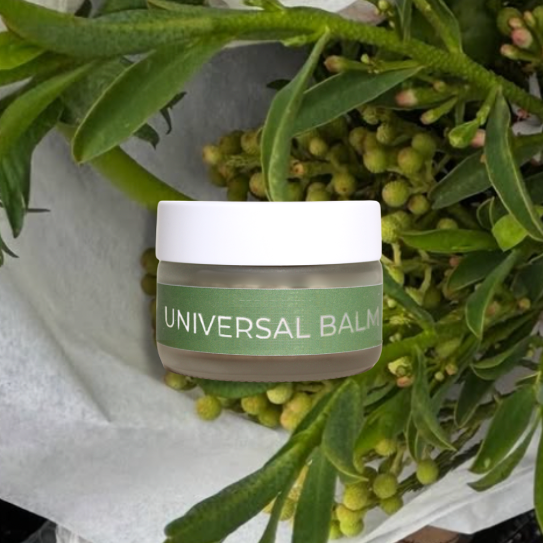 Jar of 'Universal Balm' surrounded by green leaves and flowers